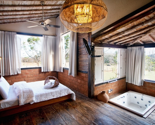 Quarto estilo rústico com banheira de hidro pequena embutida em piso de madeira.